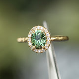 1.38ct Oval Green Montana Sapphire 18k Yellow Satin Evergreen Halo Ring in tweezers
