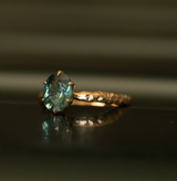 1.68ct Oval Teal Sapphire Lotus Six Prong Solitaire Ring in 14k Yellow Gold on table