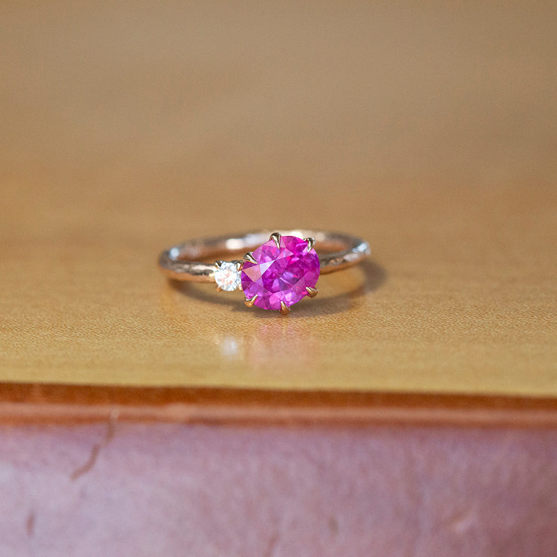 1.61ct Oval Neon Pink Sapphire and Diamond Asymmetrical Ring in 14k Rose Gold on table