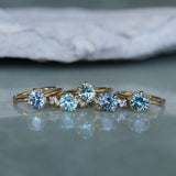 Set of gold rings with blue gemstones on a reflective surface