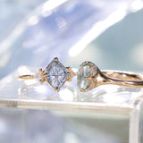 Two gold rings with gemstones on a reflective surface