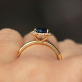 1.55ct Oval Blue Nigerian Sapphire and Diamond Four Prong Halo Ring in 14k Yellow Gold side shot on hand
