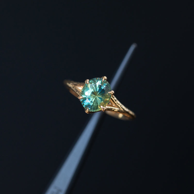 2.40ct Oval Teal Green Parti Sapphire Evergreen Carved Split Shank Six Prong Ring in 14k Yellow Gold in tweezers