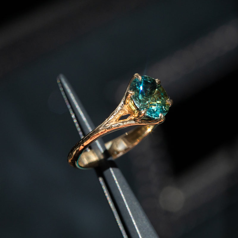 2.40ct Oval Teal Green Parti Sapphire Evergreen Carved Split Shank Six Prong Ring in 14k Yellow Gold in tweezers