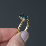 2.30ct Oval Australian Deep Teal Sapphire Evergreen Solitaire in 18k Yellow Gold in fingers