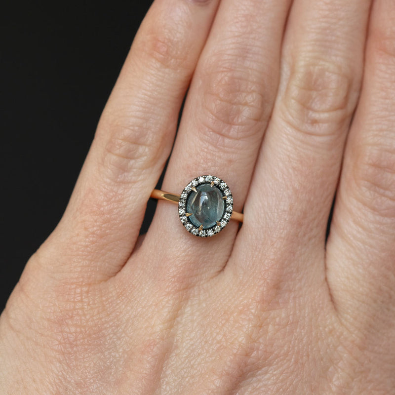 2.40ct Oval Cabochon Montana Sapphire and Antiqued Six Prong Low Profile Halo Ring in 14k Yellow Gold on hand