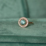 1.95ct Teal Montana Sapphire With Bezel Set Diamond Halo In 14k Rose Gold on table