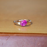1.61ct Oval Neon Pink Sapphire and Diamond Asymmetrical Ring in 14k Rose Gold on table