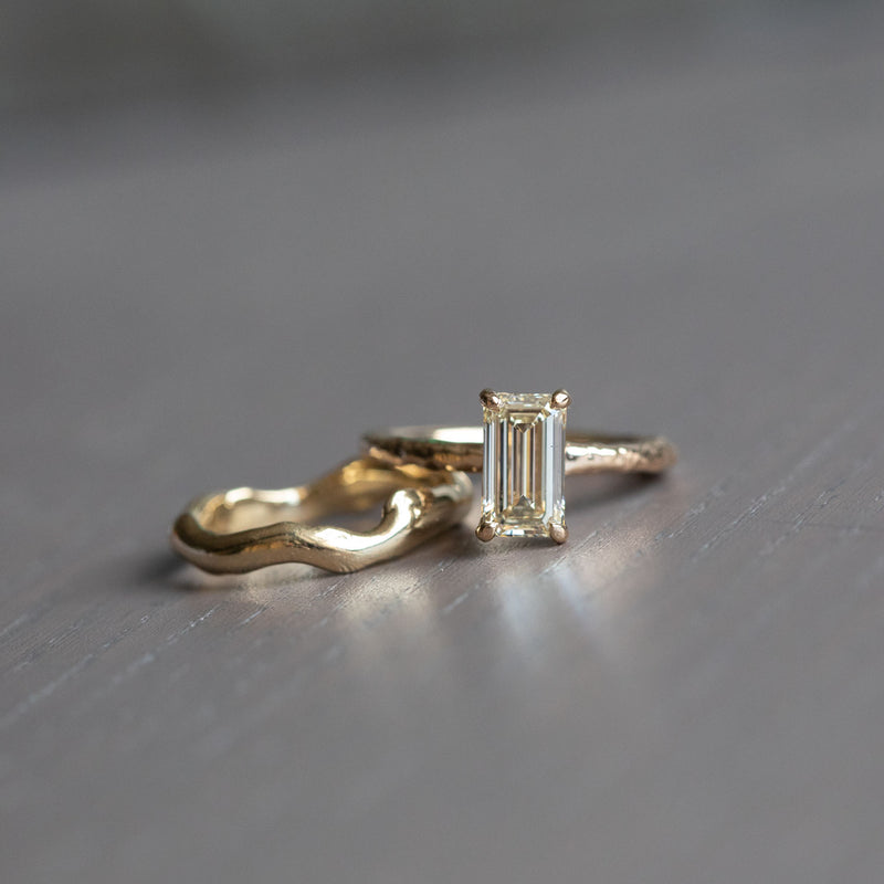 1.30ct Light Champagne Emerald Cut Diamond Solitaire Evergreen Ring In 14k Yellow Gold on table with alluvial band